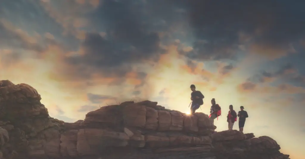 A group of hikers navigating a rocky ridge at sunrise, representing the balance, judgment, and resilience required for sustainable leadership.